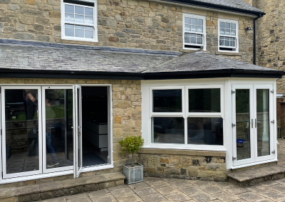 traditional stone brick home with bi-folding doors opening out onto the garden and a conservatory with white trimmed patio doors