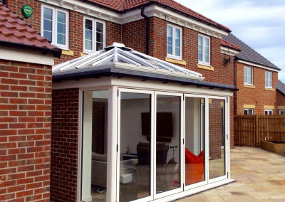 sunroom attached to modern new buld home with white bi-fold doors