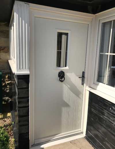 white entrance door with small glass window and black door handle