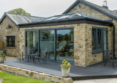 A square sandstone orangery with tinted glass