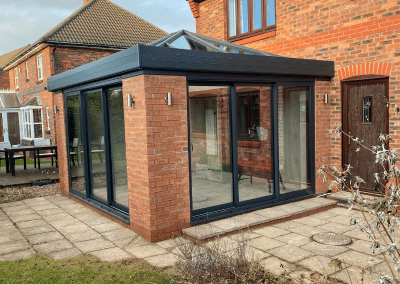 A glass and orange brick square conservatory with a glass roof