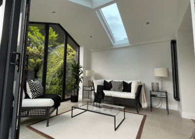 A sunroom with a sofa and coffee table, skylight and folding doors