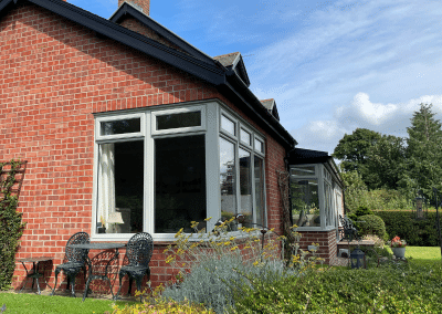 a picture of a large corner window of a cottage taken from the garden