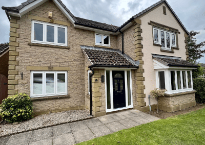 A large Beige house with a neatly kept garden and impressive windows in sets of 3