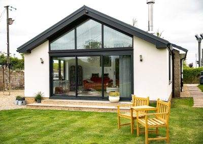 A sunroom built into the end of a house, from a garden perspective