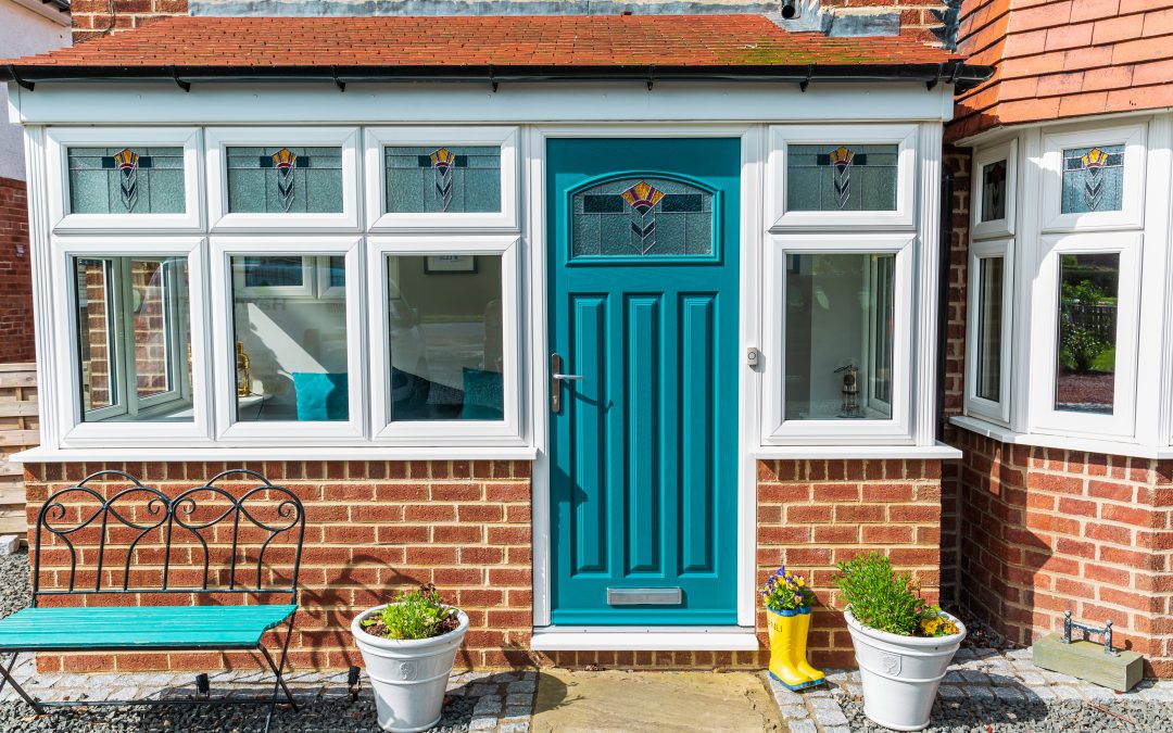 A light blue composite entrance door in a glass porch